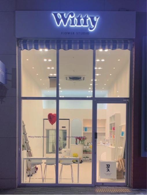 Witty 꽃집 간판 문자 뒤에 빛이 켜진 야간 모습